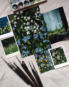 some paint brushes are sitting on a table next to paintings and watercolors,