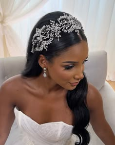 a woman sitting in a chair wearing a bridal headpiece with flowers on it