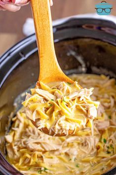 a wooden spoon full of chicken noodle soup in a crock pot with text overlay