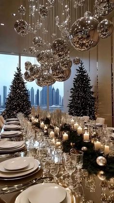 a dining room table set for christmas dinner with candles and ornaments hanging from the ceiling