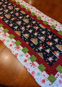 a quilted table runner on a wooden floor with snowflakes and christmas trees