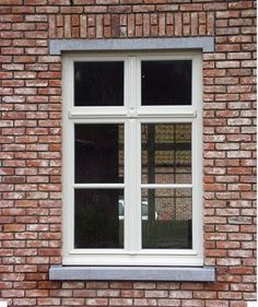 a brick wall with a white window on the top and bottom, in front of it