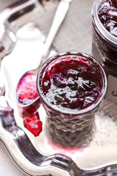 two jars of jam sitting on top of a silver tray