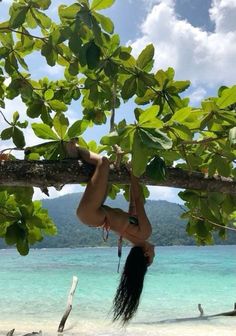 a woman hanging upside down on a tree branch