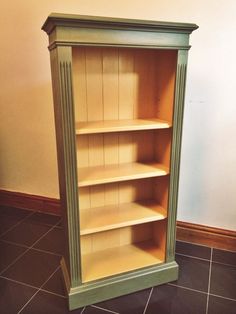 an empty green bookcase sitting on top of a tiled floor