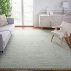 a living room with a couch, chair and large rug on the floor in front of a sliding glass door