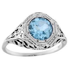 The ring has a vintage aesthetic, add a touch of classic to the ring with a delicate filigree setting. Slender threads of gold weave and swirl, forming a mesmerizing web of tiny scrolls and flourishes. The effect is both delicate and luxurious, like a whisper of old-world elegance adorning your finger. The rich, sparkling blue topaz is faceted in a round cut, in a slightly softer and more muted color of white gold setting make the ring both eye-catching and luxurious yet delicate. CHARACTERISTIC Topaz Color, White Gold Set, Filigree Ring, Muted Colors, Vintage Aesthetic, Ring Box, White Gold Rings, Solitaire Ring, Vintage Stil