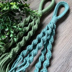 three crocheted tassels on a wooden table next to a potted plant