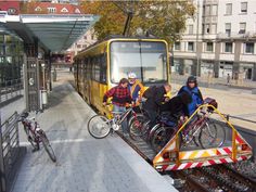 several people are loading their bikes onto the back of a train car that is stopped at a station