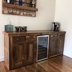 a wooden cabinet with wine glasses and bottles on the top, in front of a wall mounted wine rack