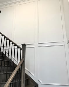 a staircase with white walls and black handrails