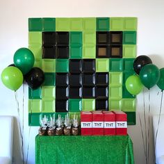 a table topped with boxes and balloons next to a wall made out of lego blocks