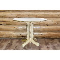 a white table sitting on top of a wooden floor next to a log cabin wall