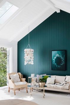 a living room with green painted walls and furniture in the center, along with a chandelier hanging from the ceiling