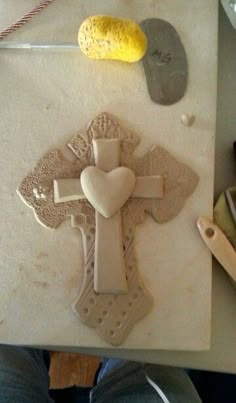 a cross made out of clay sitting on top of a table next to other items