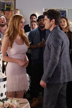 a man standing next to a woman in front of a cake