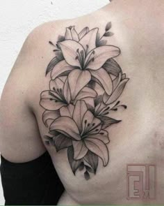 a woman's back with flowers on her shoulder and the upper part of her body