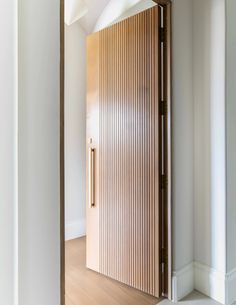 an open door in a white room with wooden slats on the wall and floor