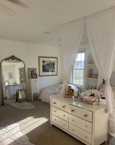 a bedroom with white furniture and curtains on the windowsill