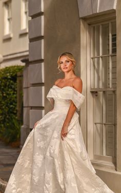 a woman in a white wedding dress standing on the steps outside an old style building