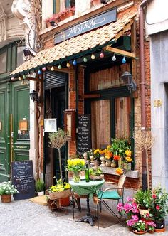 an outdoor cafe with potted plants on the outside