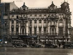 an old black and white photo of cars parked in front of a building with ornate windows