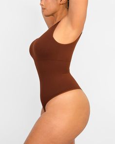 Made from recycled sculpting fabric with forward, asymmetrical cut-out detail, this bodysuit lifts and smooths. Perfect for layering under clothes or wearing alone as a super flattering all-in-one style. Why you'll love it!• Functional bodysuit with fashion.• Knitted from recycled fabric.• Built-in removable pads.• Hidden knit-in panel for 360° of tummy shaping and support.• Cool, asymmetrical cut-out detail.• Thong-cut bottom for seamless wear.• Snap closures at the bottom for easy undoing. High Cut Stretch Smoothing Bodysuit, High Cut High Stretch Bodysuit With Built-in Bra, High Cut Smoothing Bodysuit, Stretch Seamless Solid Color Bodysuit, Solid Full Coverage Stretch Bodysuit, Solid Stretch Full Coverage Bodysuit, High Stretch Smoothing Bodysuit, Full Coverage Seamless Bodysuit In Elastane, Stretch High Cut Seamless Bodysuit