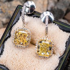 This wonderful pair of pierced earrings feature an 18K yellow gold dangle style halo setting and topped with a platinum half hoop. Each earring is accented with one (1) cushion modified brilliant cut fancy yellow colored diamond surrounded by a halo of twenty-six (26) round diamonds all prong set. The top of each earring has a half hoop containing thirteen (13) diamonds set outside and inside of the hoop and all bead set. The earrings are finished with a post and la pousette backs. The earring measure 22.7mm from top to bottom of dangle and have a width of 9.51mm. Luxury Yellow Diamond Drop Earrings, Luxury White Gold Halo Design Earrings, Formal Yellow Earrings With Halo Setting, Luxury Diamond Dangle Earrings With Halo Design, Luxury Diamond Earrings With Halo Design, Luxury Dangle Diamond Earrings With Halo Design, Luxury Gia Certified Yellow Gold Diamond Earrings, Yellow Gold Halo Setting Earrings In Sterling Silver, Luxury Halo Design Dangle Earrings