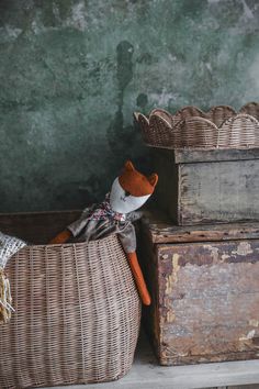 a stuffed animal in a wicker basket next to two old wooden boxes on a shelf