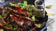 a plate topped with meat and veggies next to a bottle of sauce on a table