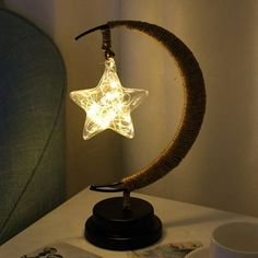 a lamp that is sitting on top of a table next to a cup and book