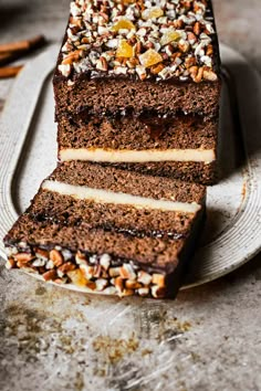 a slice of chocolate cake on a white plate with nuts and caramel toppings