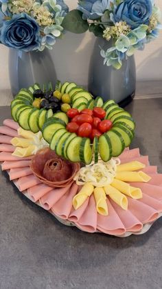 a platter filled with different types of fruit and veggies next to blue flowers