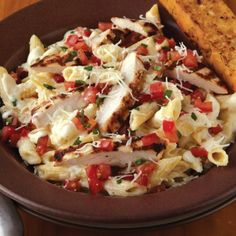 a brown plate topped with pasta and meat next to a fork on a wooden table