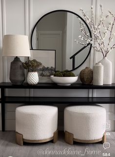 a black table with two stools and a round mirror on it's wall