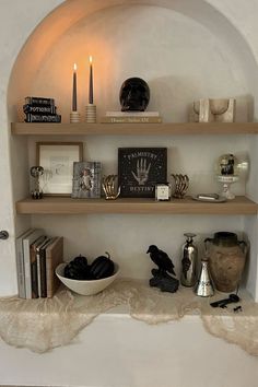 a shelf filled with books and candles on top of a wall