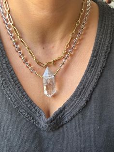 This stunning Clear Quartz Crystal Necklace is the perfect blend of elegance and spiritual energy. Featuring a striking, raw clear quartz point pendant, this necklace is hand-strung with clear quartz beads and gold-tone accents, adding a radiant touch to any outfit. The necklace is both a statement piece and a tool for spiritual healing, designed to amplify positive energies and promote mental clarity. Product Details: *Crystal: Natural Clear Quartz Point *Pendant Size: Approx. 5cm *Chain: Clear Quartz Beads with Gold-tone Spacer Beads *Chain Length: 21cm *Handmade with Love Properties of Clear Quartz: Clear Quartz is known as the "Master Healer," amplifying energy, thoughts, and the effects of other crystals. It is a highly prized stone for those looking to enhance their focus, clarity, a Clear Gemstone Beads Jewelry For Healing, Healing Clear Gemstone Beads Jewelry, Spiritual Healing Double Strand Crystal Necklaces, Clear Gemstone Necklaces For Healing, Spiritual Gold Crystal Necklaces For Layering, Spiritual Clear Gemstone Necklace, Clear Gemstone Crystal Necklaces For Jewelry Making, Clear Quartz Necklaces For Jewelry Making, Clear Quartz Crystal Necklace With Gemstone