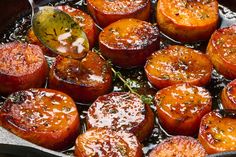 cooked tomatoes in a skillet being stirred with a wooden spoon and topped with seasoning