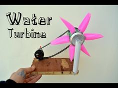 a person is holding a small pink flower on top of a piece of wood with the words water turbine written above it