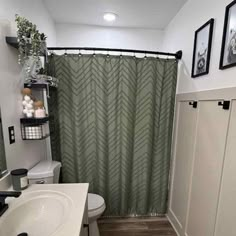 a bathroom with a green shower curtain next to a white toilet and sink in it