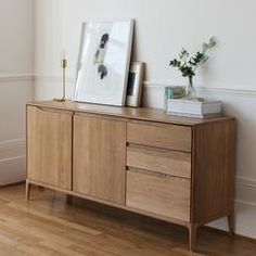 a wooden cabinet with two pictures on top of it next to a door in a room