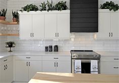 a kitchen with white cabinets and plants in the window boxes on the wall above the stove