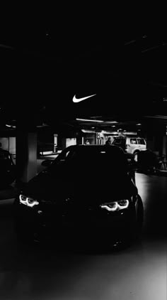 a black and white photo of cars parked in a parking garage with the lights on