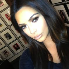 a woman with long black hair is posing for a photo in front of many framed pictures