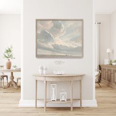 a painting hanging on the wall above a table in a room with white walls and wooden floors