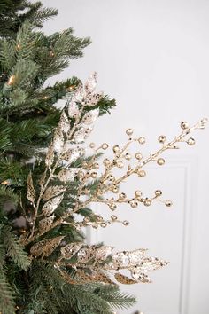 a close up of a christmas tree with gold and silver ornaments on it's branches