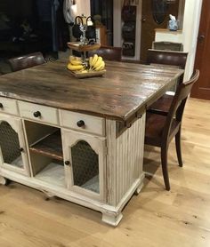 a kitchen island made out of an old wooden table with two chairs and a bowl of bananas on top