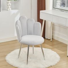 a white chair sitting on top of a wooden floor next to a mirror and table