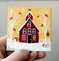 a hand holding up a small red house with trees and birds painted on the front