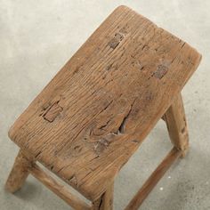 an old wooden stool sitting on concrete floor